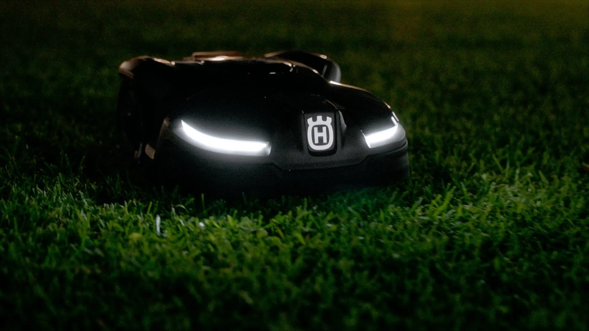Un Automower cortando de noche frente a una casa